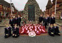 Children lay their hand-made wreath on war memorial