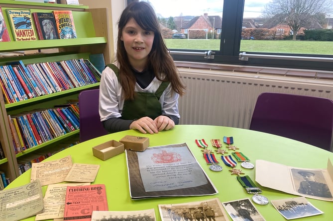 Ruby, a Year 3 pupil at Anstey Junior School in Alton, with photos of her great-grandfather, Captain Fredrick Richard Butler, plus his Second World War ration books and medals, January 2023.