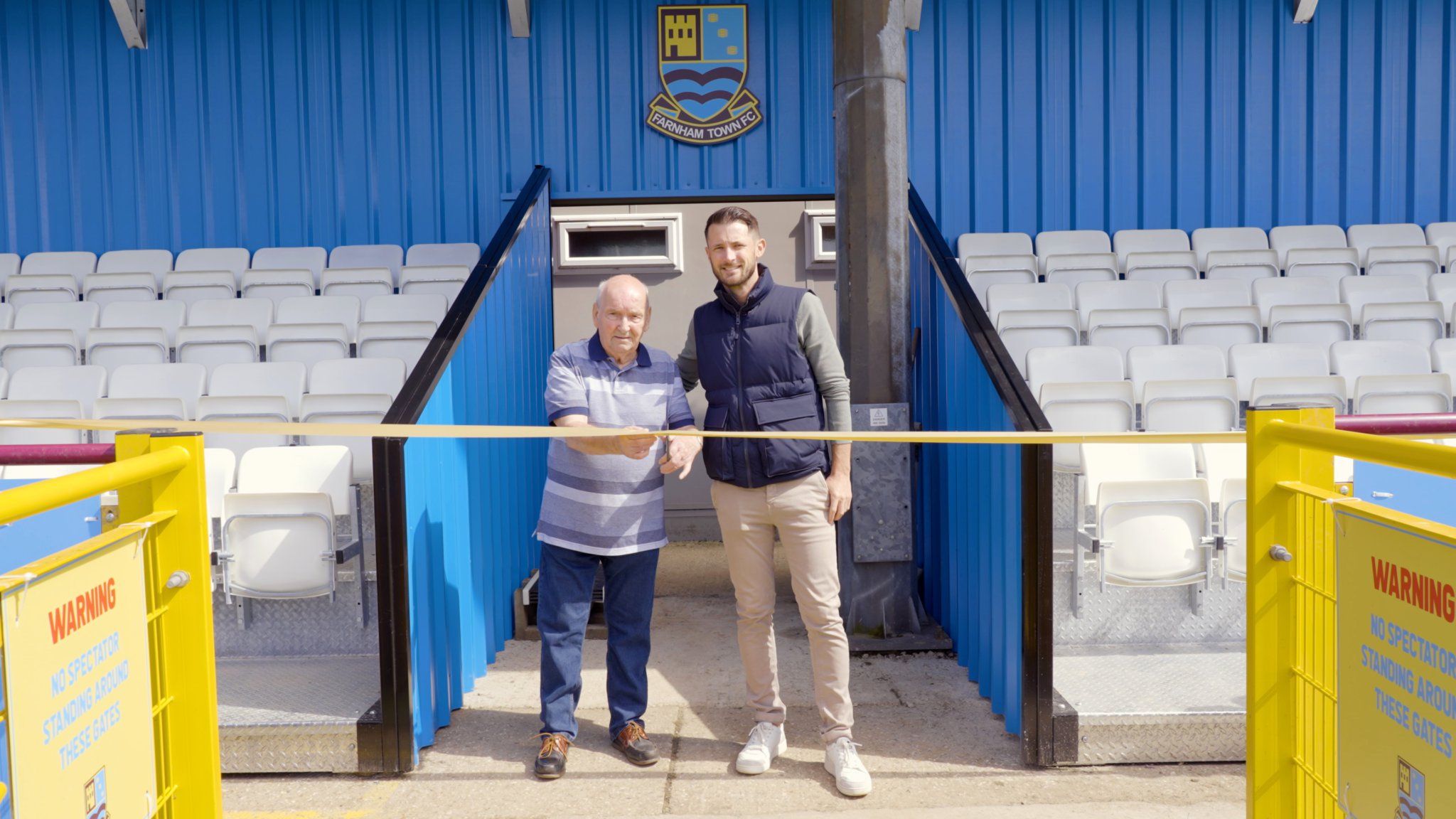Long-time Farnham supporter Ray White cuts the ribbon to officially open the SO Resi Family Stand alongside commercial director Ed Kelsing