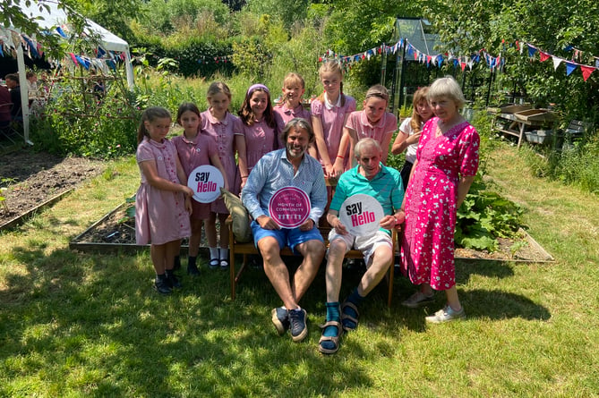 John Bishop, flanked by children from Potters Gate Primary School and garden volunteers, unveils a new bench to commemorate his visit