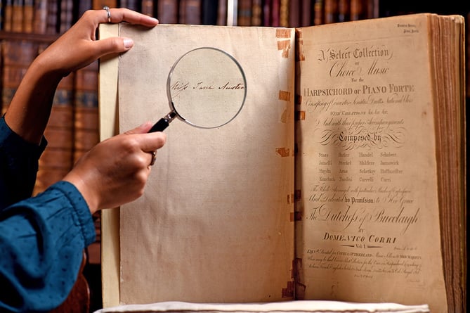 Pictured:  Clio O'Sullivan studies the music book with a magnifying glass while in the library of Chawton House, displaying Jane Austen's signature on the inside page.Jane Austen's Music book has been discovered after it was missing for 40 years© Simon Czapp/Solent News & Photo AgencyUK +44 (0) 2380 458800