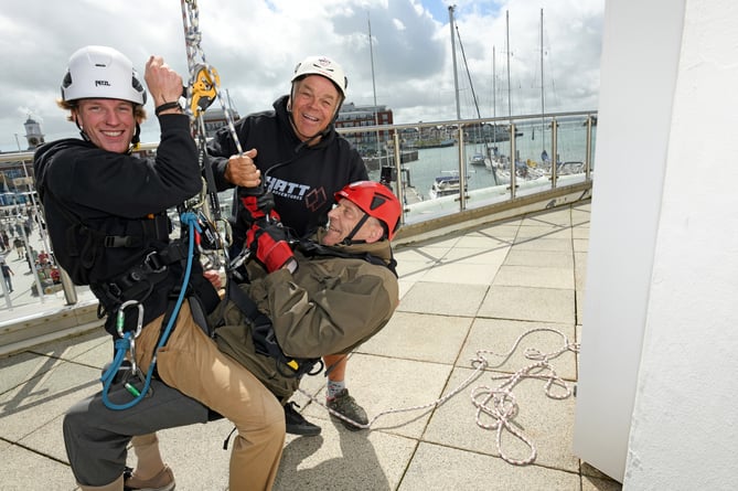 PETER WALKER SPINNAKER ABSEIL 

SPINNAKER TOWER, PORTSMOUTH, HAMPSHIRE
ENGLAND
AUGUST 2023

A 92-year-old Hampshire man undertook a charity abseil in memory of his journalist son who died in March of this year   
Hampshire's Peter Walker navigated his way down Portsmouthâs Spinnaker Tower accompanied by a professional abseiler to honour his son Jon who for many years had been the Chief Reporter at the Petersfield Post, Jon, who was 64, died just weeks after being diagnosed with terminal cancer

The Spinnaker Tower, known as 'The Sail of The Solent' is a 170 metre high observation overlooking the redevelopment of Portsmouth Harbour and the Gunwharf Quays retail complex below as well as offering a 'bird's eye view' of the adjoining Naval Base and across The Solent to the Isle of Wight 

During the summer months many people raise money for charities by experiencing the 100 metre descent and its associated adrenaline rush, but not many are 92 years of age ! 

Mr Walker Senior is aiming to raise money for Fitzroy, a charity often covered by his son which provides a range of services for adults with learning disability, autism and similar conditions.  Mr Walker, who is partially disabled and needed his doctorâs approval to undertake the challenge, said âMy son Jon was a legend because he loved Petersfield and its people and worked hard for them, for me, he is an inspiration....''I am self-sponsoring an abseil from the Spinnaker Tower to raise funds for, and to raise the profile of Fitzroy ''

Back on Terra Firma ! - Peter Walker with (left) the professional abseiler who came down with Peter and (right) a gent from the 'ground crew' 

(Photo by Malcolm Wells)
 
Standard reproduction rates apply, contact Malcolm Wells to arrange payment - Mobile: 07802-217-569 
malcolmrichardwells@gmail.com
