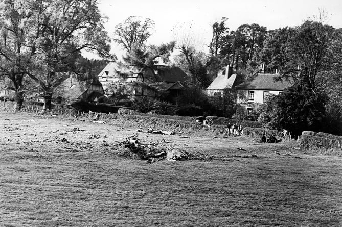 Photograph taken on November 5, 1955 and captioned: This picture, showing in the foreground the crater made by the RAF jet fighter aircraft from Odiham which crashed in Kennel Farm Paddock, Frensham, on Thursday week, indicates how narrowly the nearby farm and houses escape destruction. The pilot and his companion landed safely by parachute in the vicinity of the Farnham by-pass road. The aircraft was believed to have been Vampire XD539.