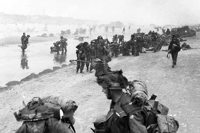 Troops of 3rd Infantry Division on Queen Red beach, Sword area, circa 0845 hrs, June 6, 1944. In the foreground are sappers of 84 Field Company Royal Engineers, part of No.5 Beach Group, identified by the white bands around their helmets. Behind them, medical orderlies of 8 Field Ambulance, RAMC, can be seen assisting wounded men. In the background commandos of 1st Special Service Brigade can be seen disembarking from their LCI(S) landing craft.