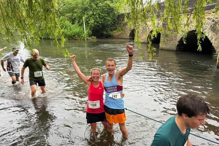 Farnham Runners' Leza Millington and Richard Denby pause for a photo in the River Wey crossing, the final stage of the Elstead marathon
