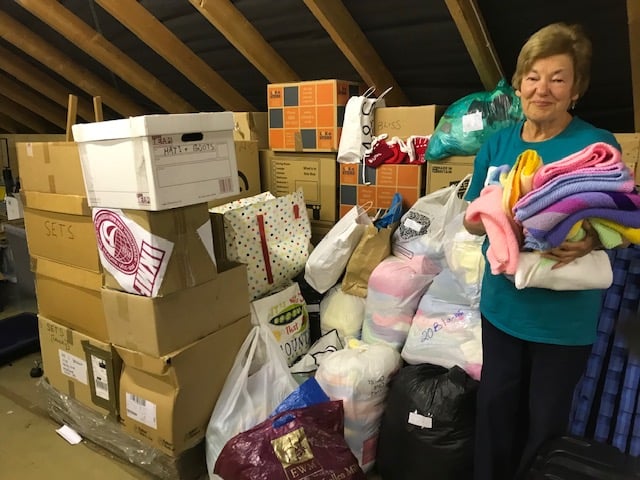Dianne Bennett with the mountain of knits building up ready for packing
