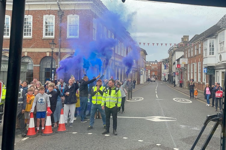 Flares are lit as the Farnham Town FC open-top bus tour enters the town centre.