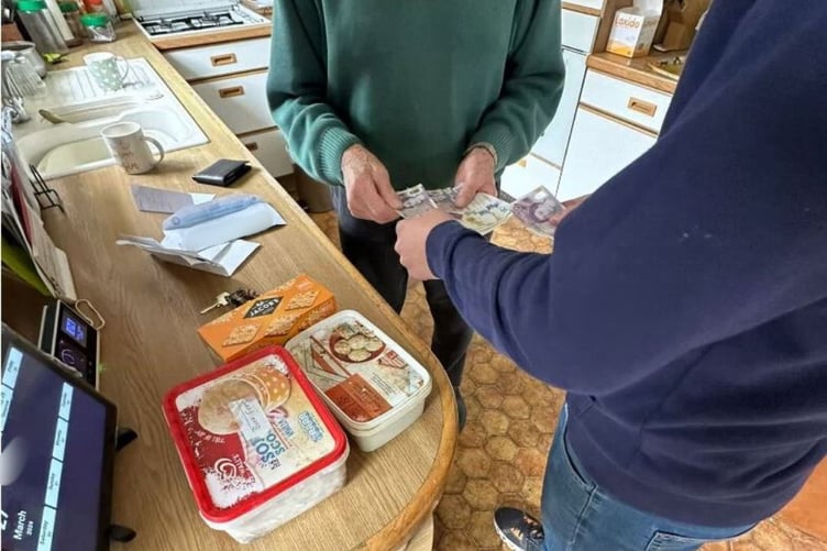 A victim handing over cash to rogue roofers in Woking.