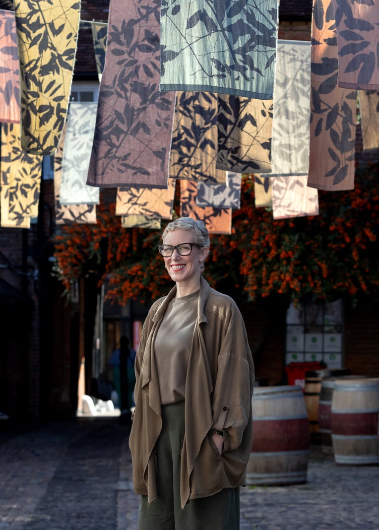 Farnham textile artist Hermione Thomson beneath her colourful Fleeting installation in Lion and Lamb Yard.